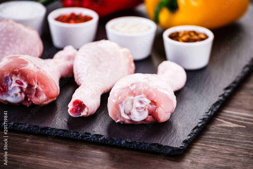 Raw chicken drumsticks on wooden background