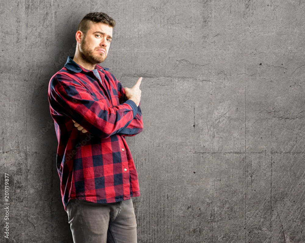 Young handsome man pointing away side with finger Young handsome man pointing away side with finger