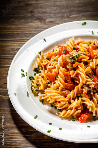 Pasta with tomato sauce and vegetables on wooden table