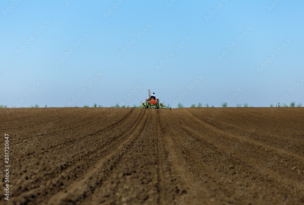 Farmer in old fashioned tractor sowing in field. Farmer in old fashioned tractor sowing in field.