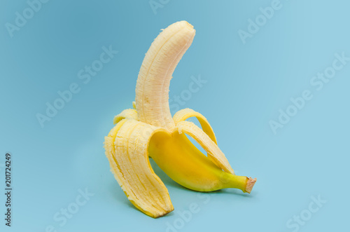 Fresh peeled banana on blue background