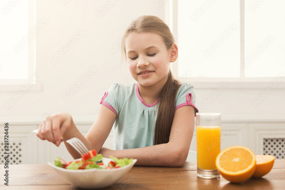 Child girl eating fresh salad and drinking orange juice Child girl eating fresh salad and drinking orange juice