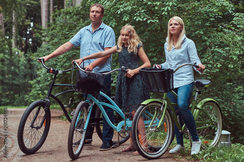 Attractive family dressed in casual clothes on a bicycle ride with their cute little spitz dog.