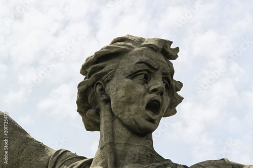 Head of female statue with open mouth on the cloudy sky background