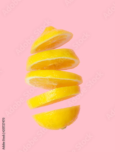 Flying lemon. Sliced lemon isolated on gradient pink background. Levity fruit