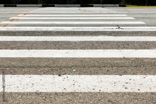 white stripes of a pedestrian crossing across the road