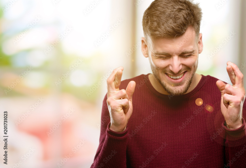 Handsome young man with crossed fingers asking for good luck Handsome young man with crossed fingers asking for good luck