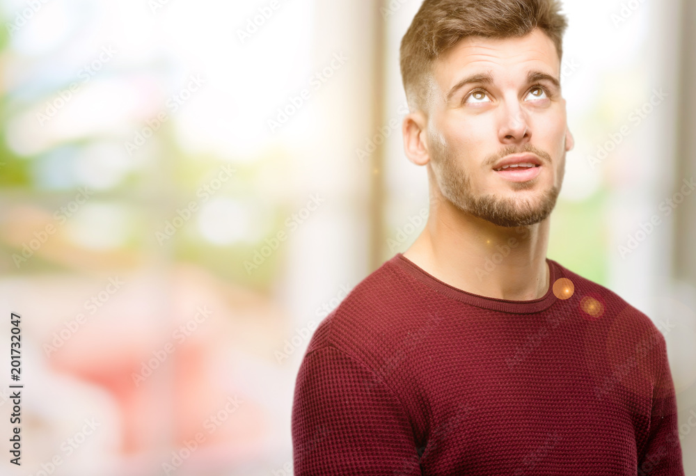 Handsome young man confident and happy with a big natural smile laughing looking up Handsome young man confident and happy with a big natural smile laughing looking up