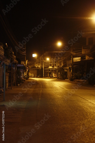 remote thai town main street at night time with rows of yellow shining street lights, Northern Thailand, Southeast Asia