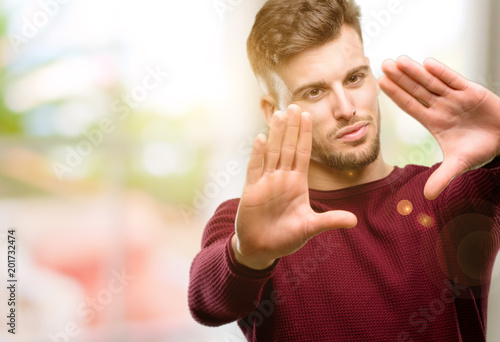 Handsome young man confident and happy showing hands to camera, composing and framing gesture