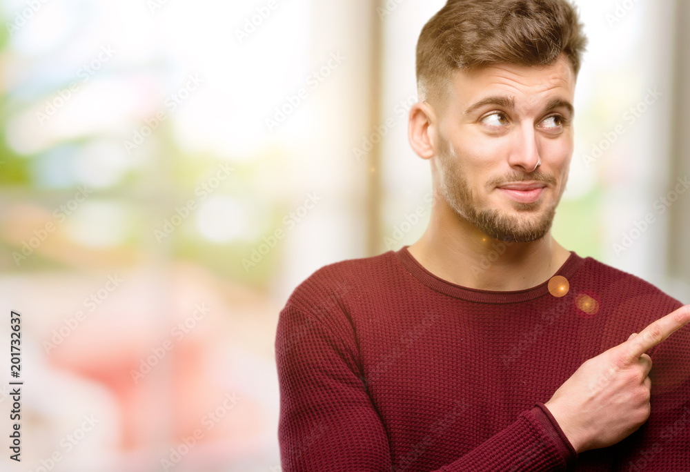 Handsome young man pointing away side with his finger Handsome young man pointing away side with his finger