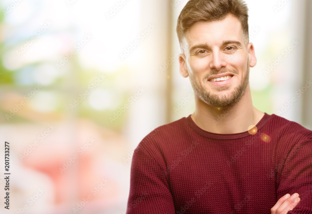 Handsome young man with crossed arms confident and happy with a big natural smile laughing Handsome young man with crossed arms confident and happy with a big natural smile laughing