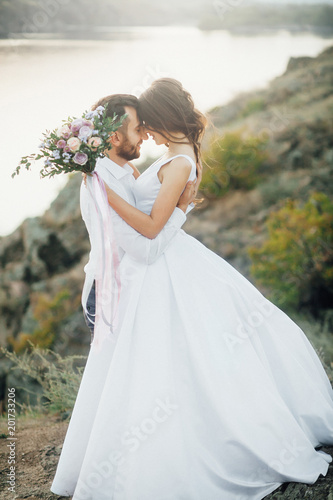 Wedding couple embrance at the walk with mountain and river at the background. Outdoors
