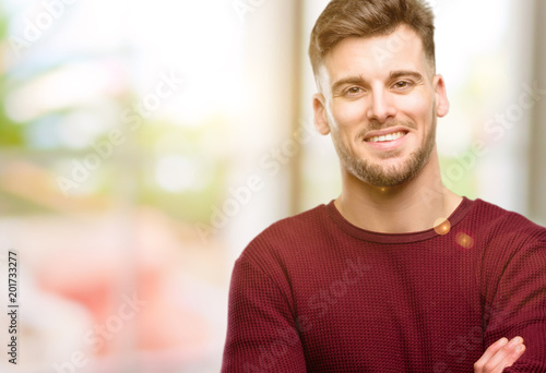 Handsome young man with crossed arms confident and happy with a big natural smile laughing