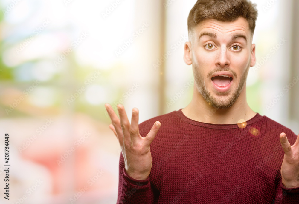 Handsome young man happy and surprised cheering expressing wow gesture Handsome young man happy and surprised cheering expressing wow gesture