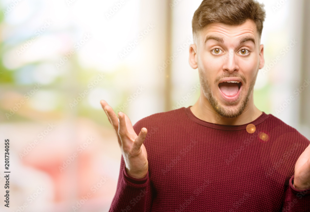 Handsome young man happy and surprised cheering expressing wow gesture Handsome young man happy and surprised cheering expressing wow gesture