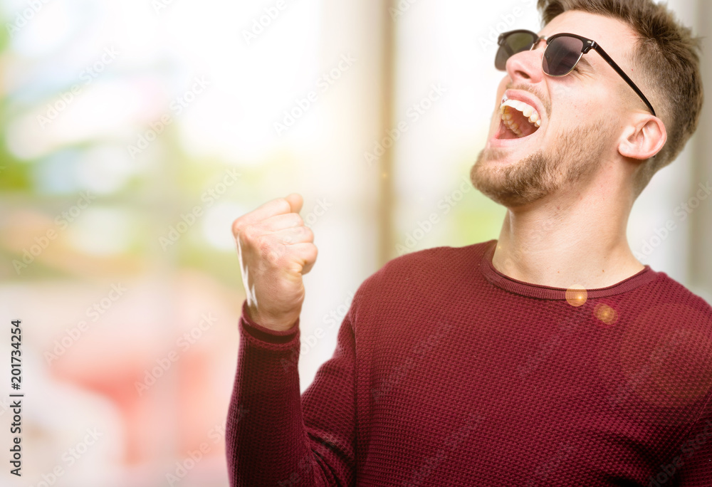 Handsome young man happy and excited celebrating victory expressing big success, power, energy and positive emotions. Celebrates new job joyful Handsome young man happy and excited celebrating victory expressing big success, power, energy and positive emotions. Celebrates new job joyful