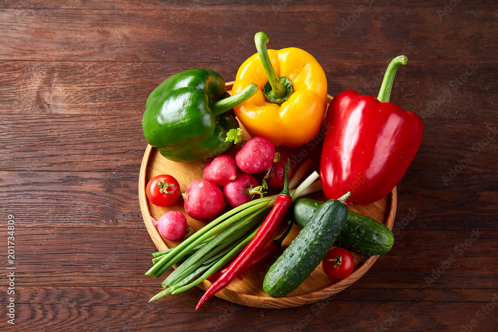 Wooden plate with vegetables for a vegetarian salad on rustic wooden background, close-up, selective focus Wooden plate with vegetables for a vegetarian salad on rustic wooden background, close-up, selective focus