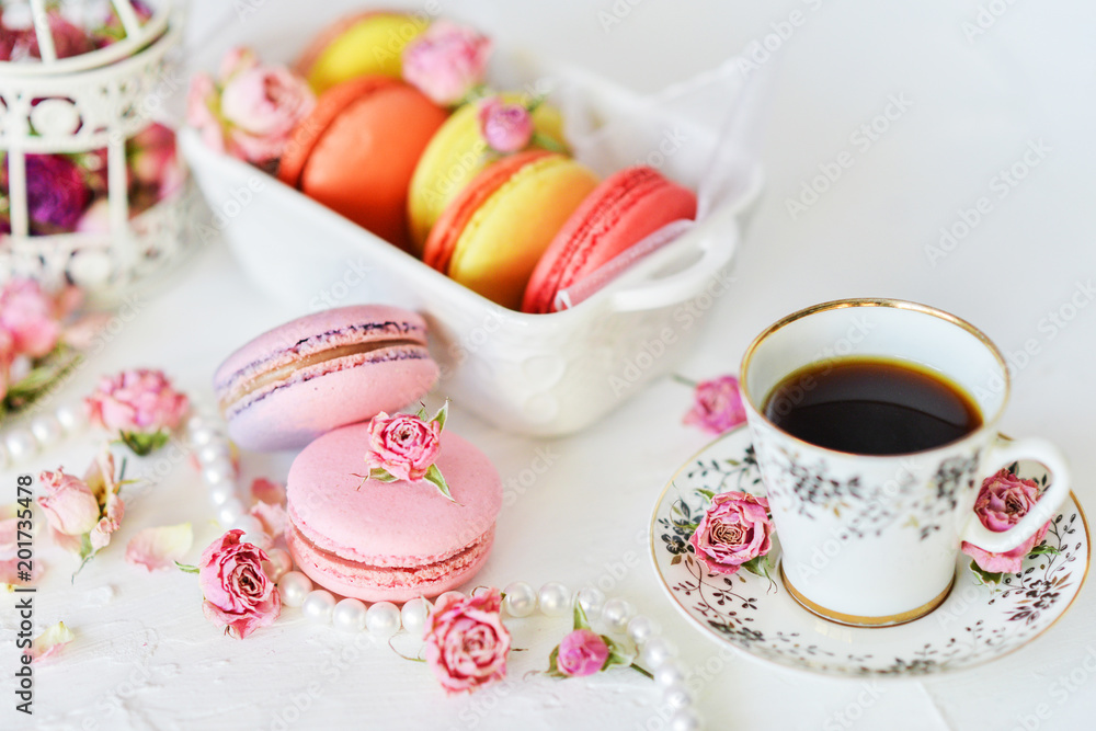 Dessert: A Delicate Fresh Colorful French Macaroons In Pastel Colors With Flowers Roses On A Light Textile Background, Top View Dessert: A Delicate Fresh Colorful French Macaroons In Pastel Colors With Flowers Roses On A Light Textile Background, Top View