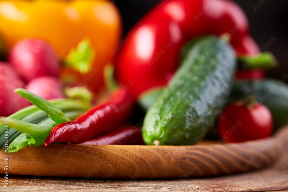 Composition of vegetables on flat plate on wooden table, close-up, selective focus Composition of vegetables on flat plate on wooden table, close-up, selective focus