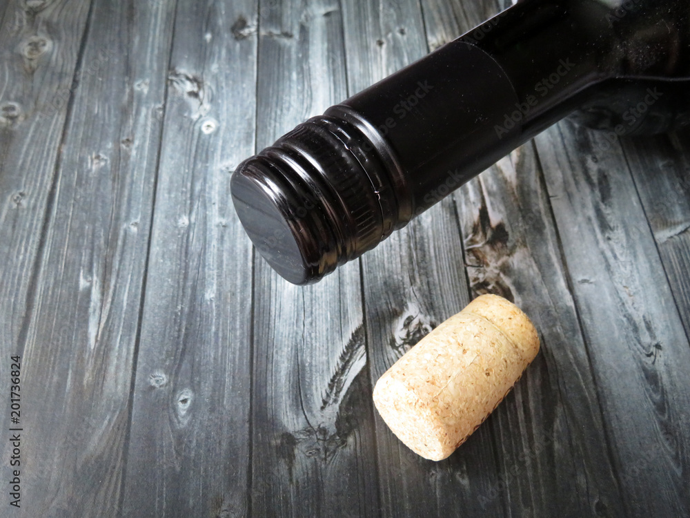 Bottle of wine and cork on a dark wooden table