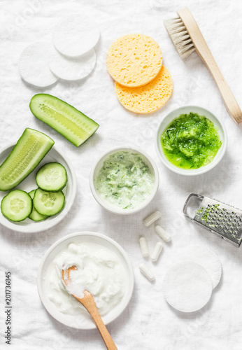 Calming cucumber yogurt mask. Ingredients for homemade cucumber face mask-cucumber, natural yogurt, probiotic capsule, sponges, brush on white background, top view. Flat lay