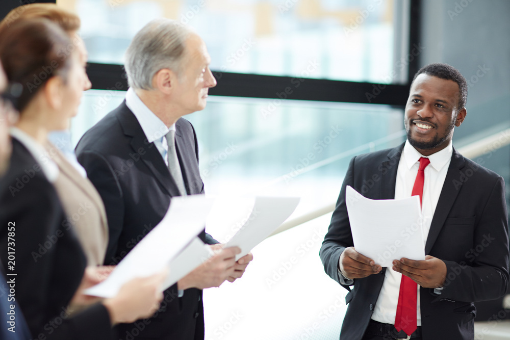 Young successful African-american financier making report for colleagues about changes on stock market Young successful African-american financier making report for colleagues about changes on stock market