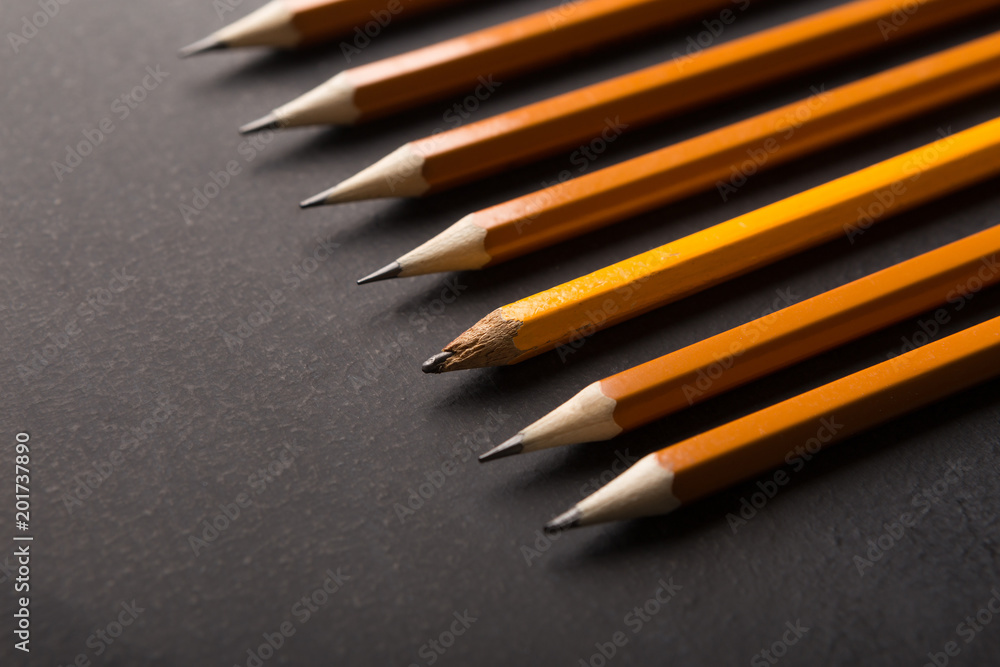 One old and plenty of new pencils on black background One old and plenty of new pencils on black background