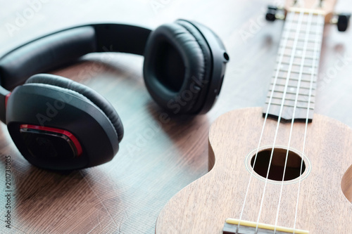 Headphones and acoustic guitar ukulele brown on wooden floor. © Photo Sesaon
