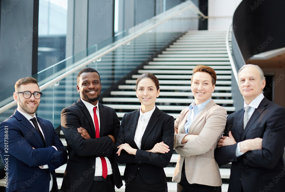 Row of smiling colleagues in formalwear crossing their arms on chest while looking at you Row of smiling colleagues in formalwear crossing their arms on chest while looking at you