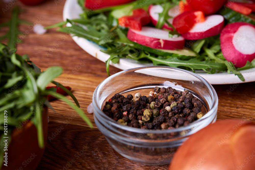 Fresh red radish in wooden bowl among plates with vegetables, herbs and spicies, top view, selective focus. Fresh red radish in wooden bowl among plates with vegetables, herbs and spicies, top view, selective focus.