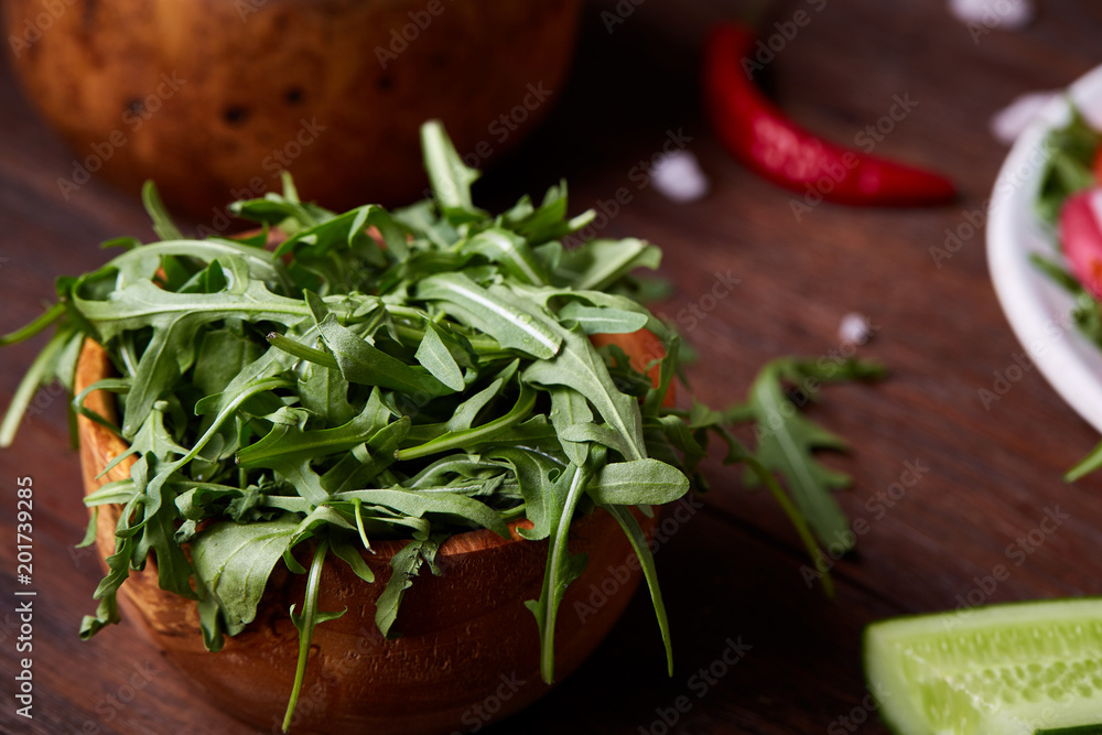 Fresh red radish in wooden bowl among plates with vegetables, herbs and spicies, top view, selective focus. Fresh red radish in wooden bowl among plates with vegetables, herbs and spicies, top view, selective focus.