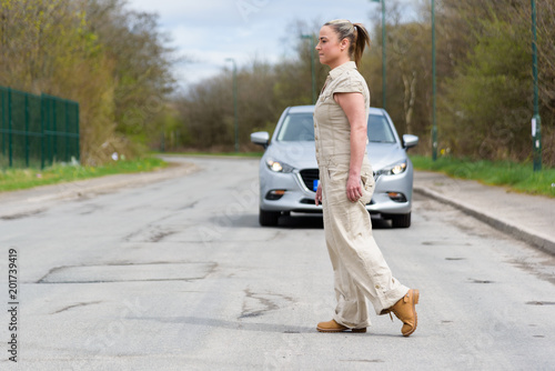 Woman crossing the road, with a car approaching behind her