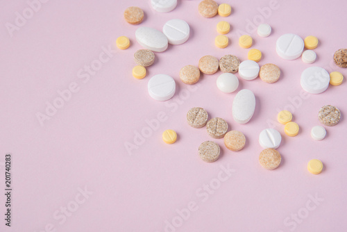 Different tablets and pill in the package and without it on a pink background