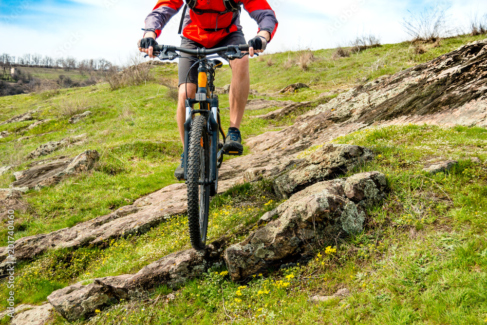 Obraz premium Cyclist in Red Jacket Riding Mountain Bike Down Rocky Hill. Extreme Sport and Adventure Concept.