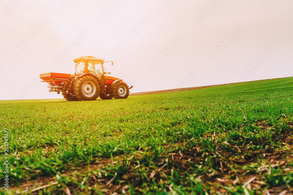 Farmer in tractor fertilizing wheat field at spring with npk Farmer in tractor fertilizing wheat field at spring with npk