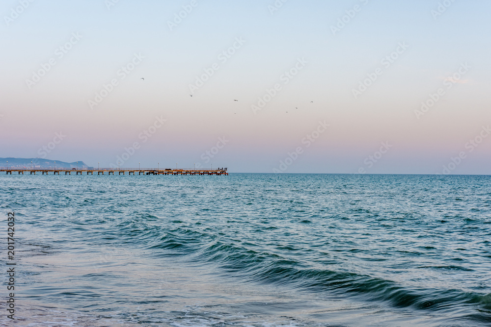 blue sea and waves. On the pier are fishermen