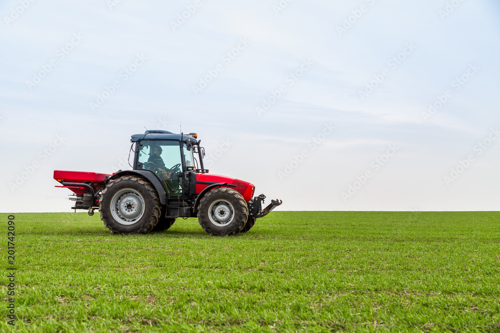 Farmer in tractor fertilizing wheat field at spring with npk Farmer in tractor fertilizing wheat field at spring with npk