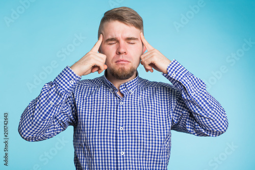 Young man holds fingers on temples, has bad memory, tries to concentrate and remember. Man has headache, feels tired