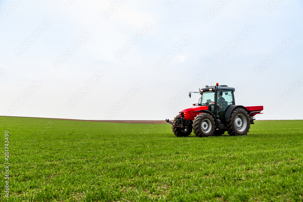 Farmer in tractor fertilizing wheat field at spring with npk Farmer in tractor fertilizing wheat field at spring with npk