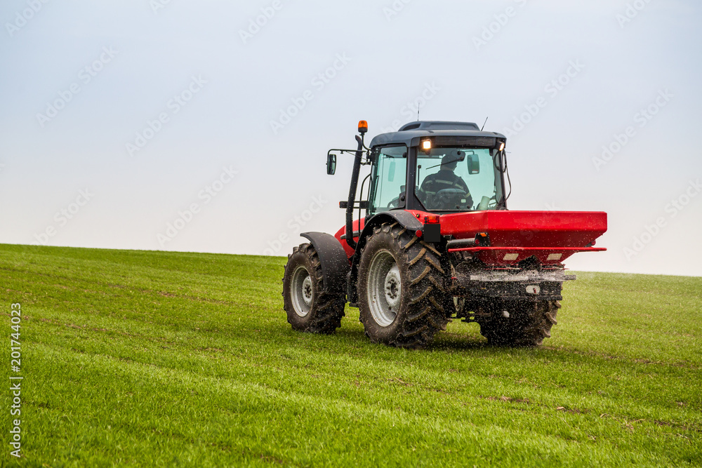 Farmer in tractor fertilizing wheat field at spring with npk Farmer in tractor fertilizing wheat field at spring with npk