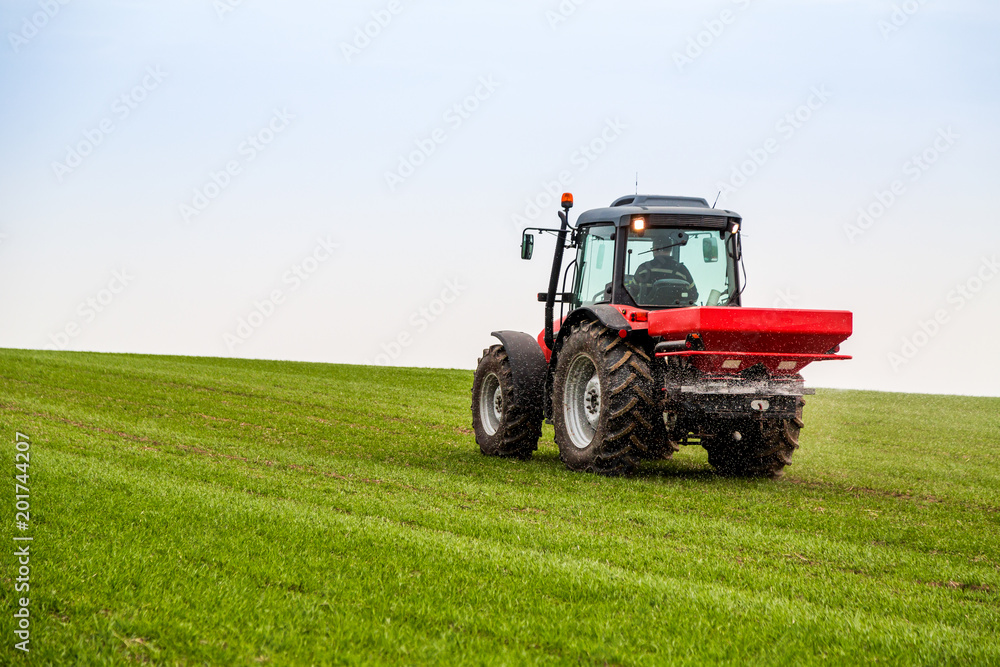 Farmer in tractor fertilizing wheat field at spring with npk Farmer in tractor fertilizing wheat field at spring with npk