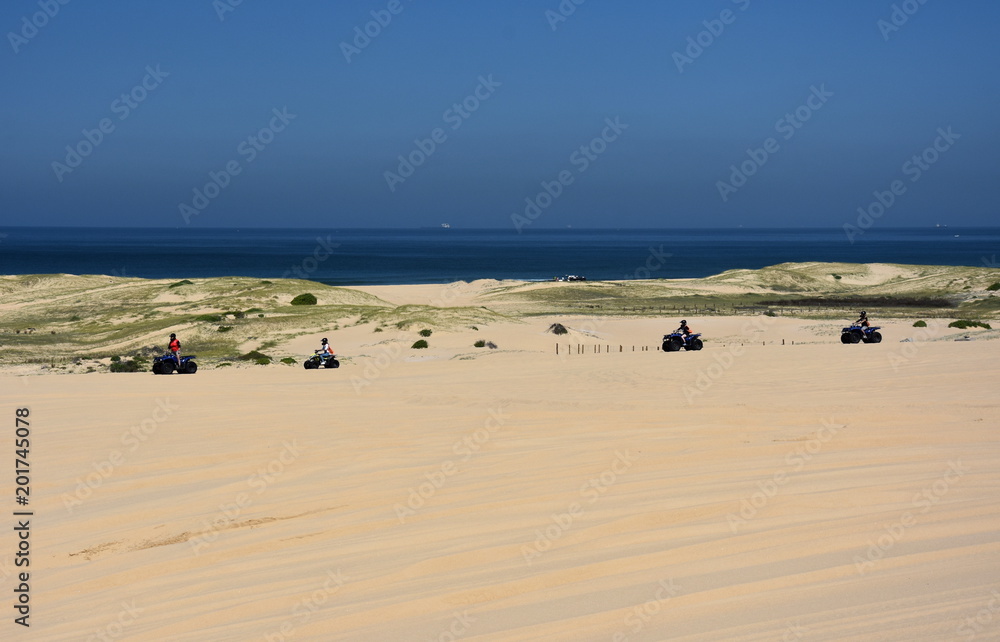 Happy quad bikers driving in sand dunes at Anna bay (Newcastle, NSW, Australia). Active people in outdoor activity driving quad on coastal desert beach. Happy quad bikers driving in sand dunes at Anna bay (Newcastle, NSW, Australia). Active people in outdoor activity driving quad on coastal desert beach.
