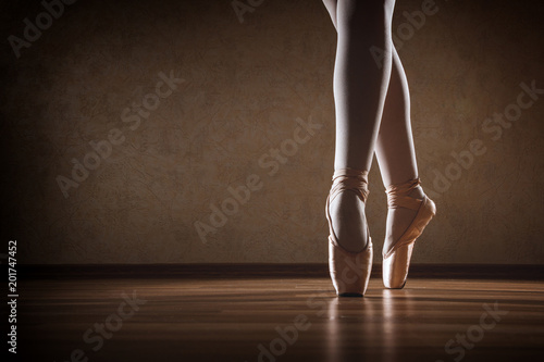 The girl in Pointe stands on the wooden floor in the contour light