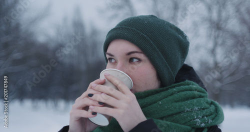 teenage girl drinking hot cocoa in park on a winter day © GCapture