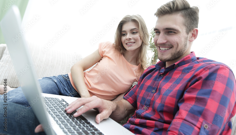 Happy modern couple surfing the net and working on laptop at home Happy modern couple surfing the net and working on laptop at home