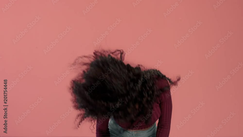 woman with long curly hair dancing and shaking hair and smiling. Have fun shaking head on pink background woman with long curly hair dancing and shaking hair and smiling. Have fun shaking head on pink background