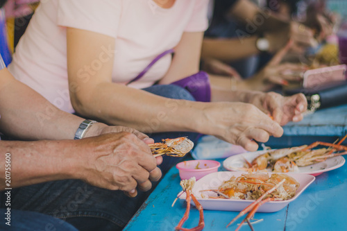The Couple tourists are eating shrimp at Amphawa, Samut Songkhram, Thailand.