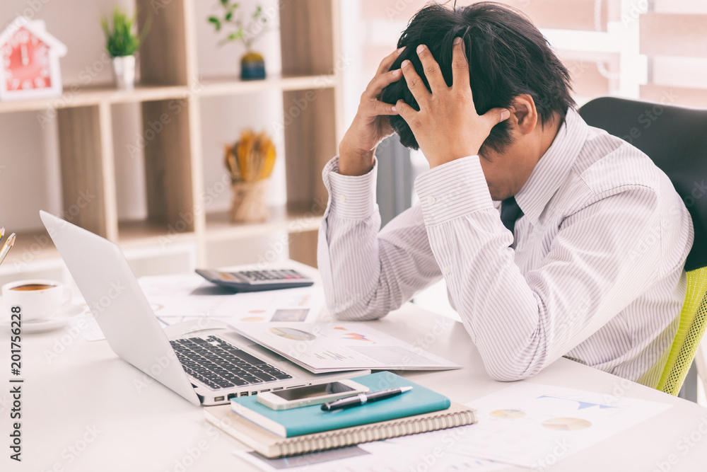 The man are stressed at work in the office. Asian businessman stressful and headache with laptop computer. Young male with headache at office, feeling sick at work. The man are stressed at work in the office. Asian businessman stressful and headache with laptop computer. Young male with headache at office, feeling sick at work.