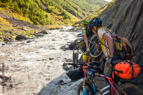 Mountain biker is crossing the river in the highlands of Tusheti region  Georgia
